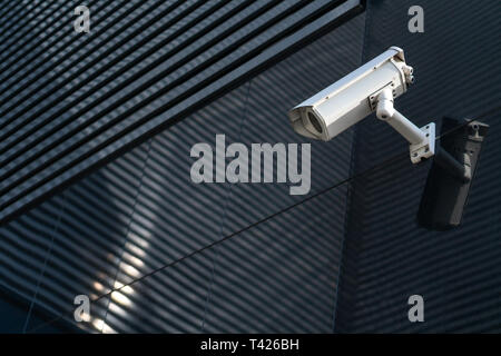 Photo of Modern CCTV camera on a wall. A blurred night cityscape background. Concept of surveillance and monitoring. Toned image double exposure mock  Stock Photo