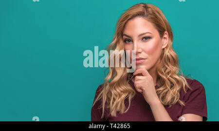 Young attractive blonde on a blue background. Stock Photo