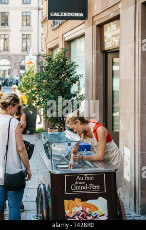 Strasbourg, France - Jul 22, 2017: Young blonde woman serving customer with french bio home-made - ice-cream parlor in central Strasbourg France  Stock Photo