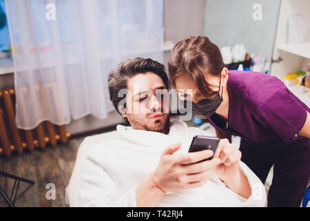 man and doctor before plastic surgery. Doctor holding tablet and talking to her patient. Stock Photo