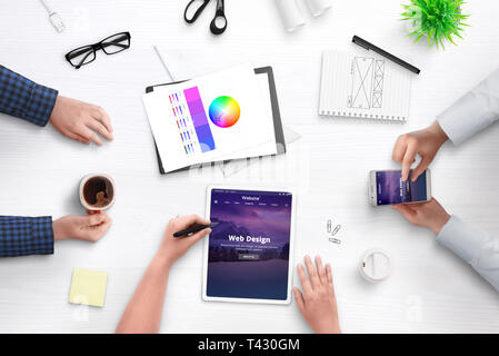 Development theme for content managment system concept. Office desk, flat lay with people, mobile devices, papers, cofffee. Stock Photo
