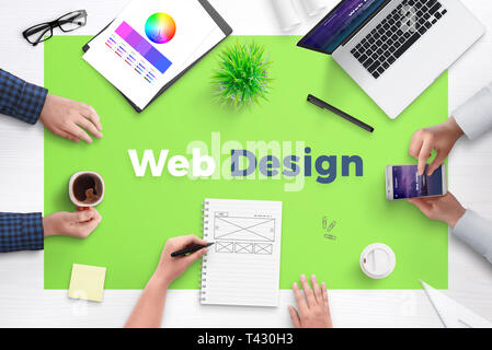 Web design text on office desk. Concept of web development team work space. Flat design flat page on laptop and smart phone. Stock Photo