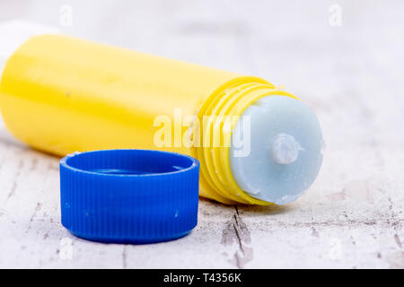 yellow glue stick with blue lid on rustic white wood Stock Photo