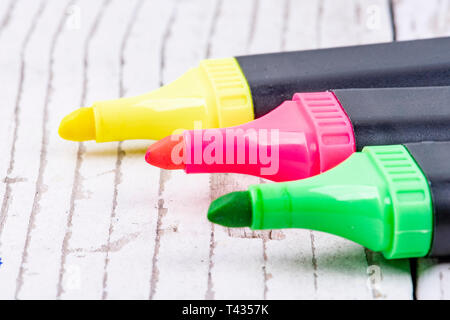 three highlighters in yellow pink and green on rustic white wood Stock Photo