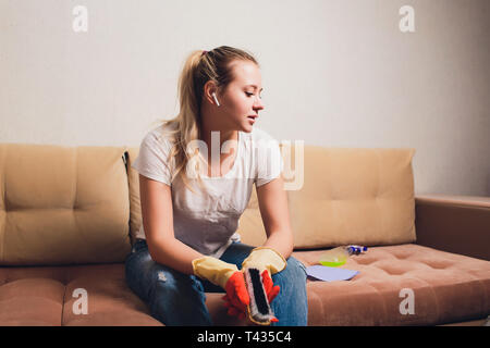 Tired woman having rest after cleaning home, lying on sofa in the living-room, copy space. Housekeeping and home cleaning concept. Stock Photo