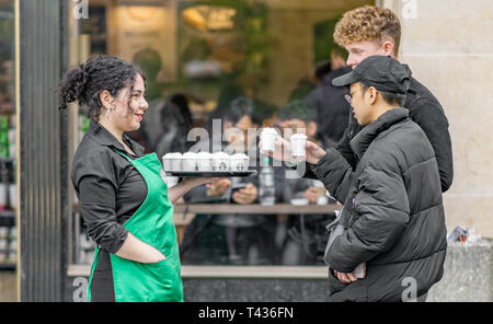 A female Starbucks employee hands out warm samples to the Public in Prague old town square Stock Photo