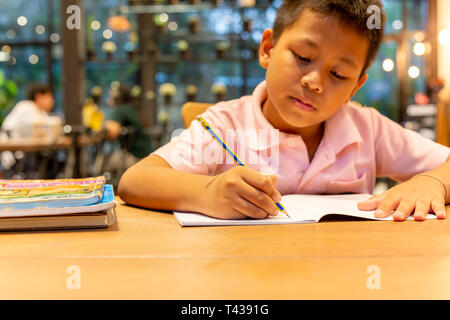 Asian schoolboy hand with pencil doing his homework at home Stock Photo