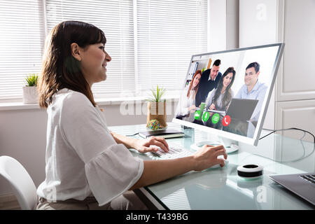 Businesswoman Videoconferencing With Her Colleagues On Computer At Workplace Stock Photo