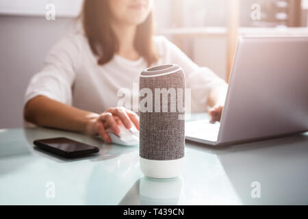 Smiling Young Woman Using Voice Assistant In Office Stock Photo