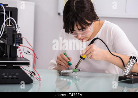 Female Engineer Or Tech Repairs Electronic Device In Hardware Repair Shop Stock Photo