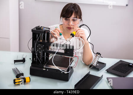 Female Engineer Or Tech Repairs Electronic Device In Hardware Repair Shop Stock Photo