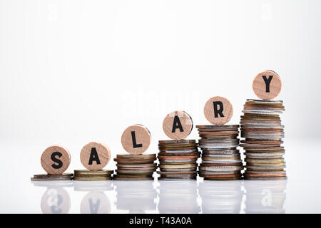 Salary Wooden Block Text Over Increasing Stack Of Coins Over There Reflective Surface Stock Photo