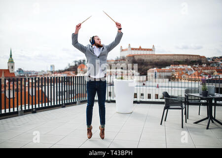 A young businessman with headphones standing on a terrace, having fun. Stock Photo