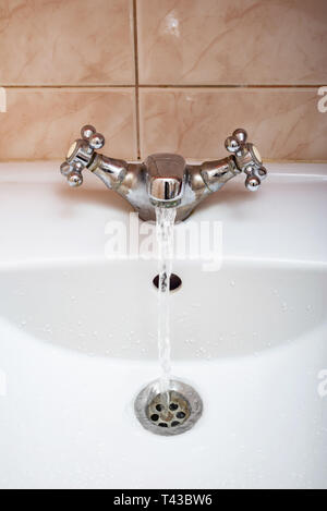 Vertical image of a tap with water flowing strongly under high pressure Stock Photo