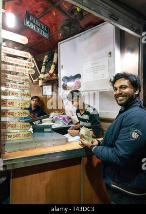 Vertical view of a customer being served at a streetfood parcel counter in Kolkata aka Calcutta, India. Stock Photo