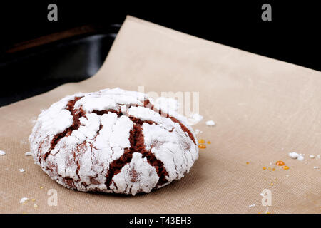 Chocolate cookies with cracks on baking paper and iolated on black. Cracked chocolate biscuits. Stock Photo