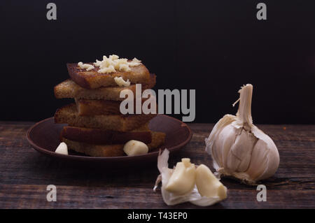Homemade croutons with garlic. Croutons on the plate. Dark still life. Stock Photo