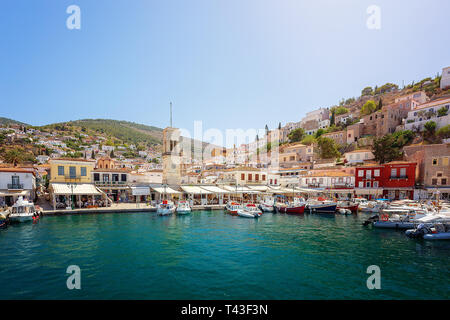 Hydra, Greece - June 2, 2018: Beautiful harbor with cycladic architecture hillside town behind, on the Greek Island of Hydra. Central Clock tower in H Stock Photo
