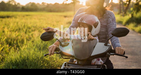 mom and child enjoy riding motorcycle scooter togehter Stock Photo