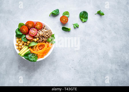 Buddha bowl salad with buckwheat, avocado, carrot, tomato, spinach, chickpea on grey. Healthy vegetarian vegan diet eating, super food. Top view, copy Stock Photo