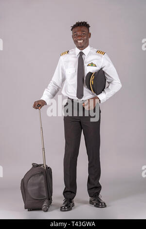 April 2019.  A young airline pilot with an african dred hairstyle and flight bag on wheels. Stock Photo