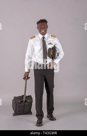 April 2019.  A young airline pilot with an african dred hairstyle and flight bag on wheels. Stock Photo