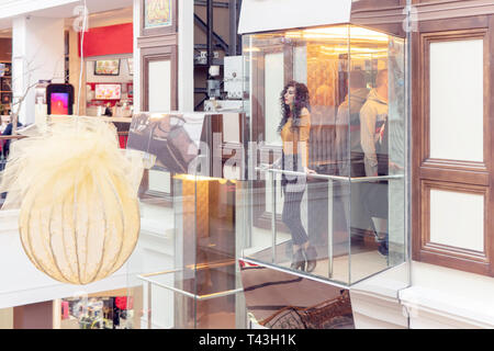 pensive woman riding in a glass elevator leaning on the railing Stock Photo