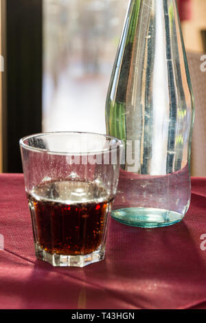 A beautifully backlit glass of red soft drink on a restaurant table in Italy at sunset Stock Photo
