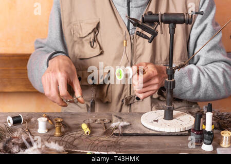 Man making trout flies. Fly tying equipment and material for fly fishing  preparation Stock Photo - Alamy