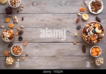 Mixed nuts and dried fruits in wooden bowl on wooden background, copy space. Healthy snack - mix of organic nuts and dry fruits. Stock Photo