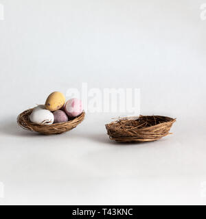 Easter eggs in a one nest with an empty nest next to it Stock Photo