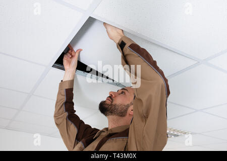 Close-up Of Young Electrician Repairing Ceiling In Office Stock Photo