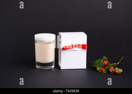 White colored blank cosmetic container for face cream moisturizer on black background. Skincare candle cream with box and green coffee. Christmas conc Stock Photo