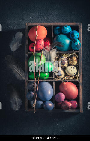 Top view of various Easter eggs in small wooden box Stock Photo