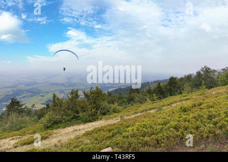 A flying paraglider against the blue sky, in the morning fog of the Carpathian Mountains Stock Photo