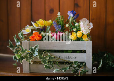 a vintage wooden crate filled with pretty silk flowers Stock Photo