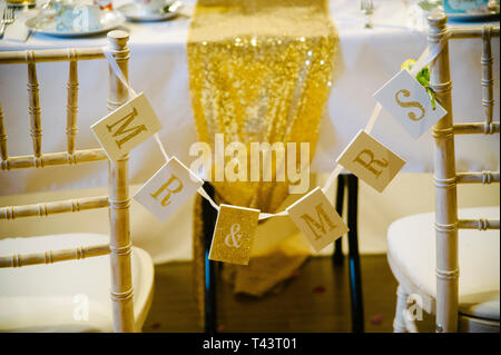 mr & mrs sign bunting tied to wooden chairs at boho wedding reception. Shabby chic wedding ideas Stock Photo