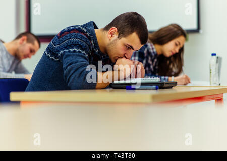 Students sitting in an exam hall doing an exam in university Stock Photo