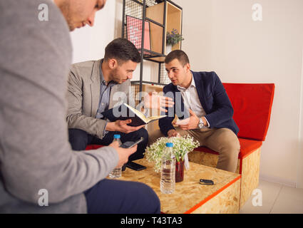 Two young entrepreneurs discussing their businesses while sitting in a casual office spot. Stock Photo