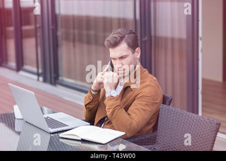 Handsome Young Adult Man Working at Home, Home Office with Laptop and Smartphone Stock Photo