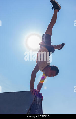 Yound healthy man doing handstand in skatepark Stock Photo