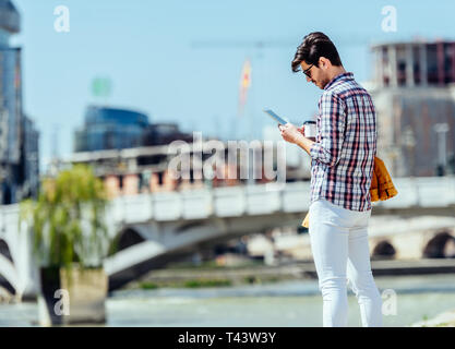 Urban businessman using PC tablet near river Stock Photo