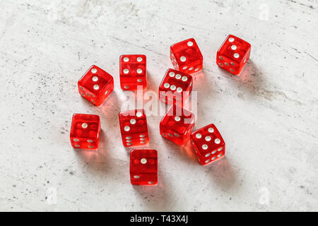 10 translucent red dices on white concrete board. Stock Photo