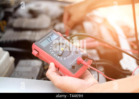 auto mechanic check car battery voltage by voltmeter multimeter at repair service station Stock Photo