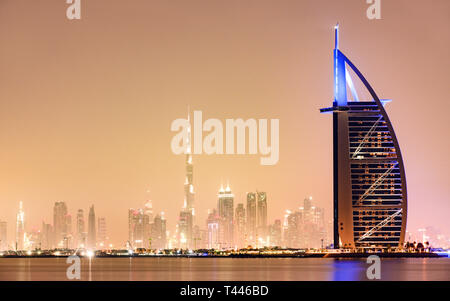 Stunning view of the illuminated Dubai skyline during sunset with the magnificent Burj Khalifa in the background and a luxury hotel in the foreground. Stock Photo