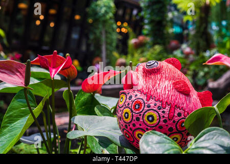 Cute colorful fish statue and Red anthurium flowes ( tailflower, flamingo flower, laceleaf ) decoration in the garden Stock Photo