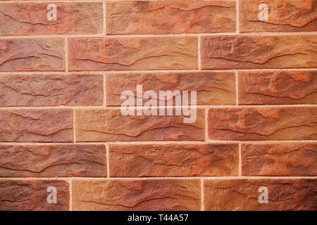 Red brick wall. Decorative brick with artificial defects and cracks. Texture of decorative tiles in form of brick. Stock Photo