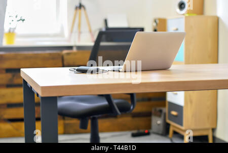 Empty office desk, laptop with connected generic usb device on it, blurred chair and furniture background Stock Photo