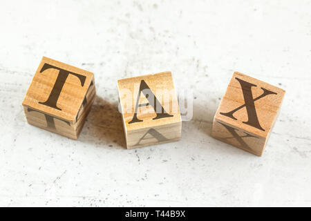 Three wooden cubes with word TAX on white board. Stock Photo