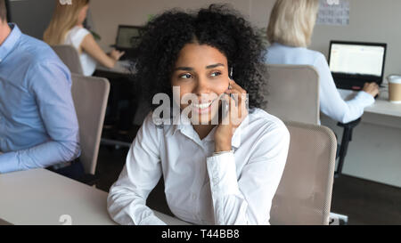 Smiling african american employee talking on phone sitting in office Stock Photo